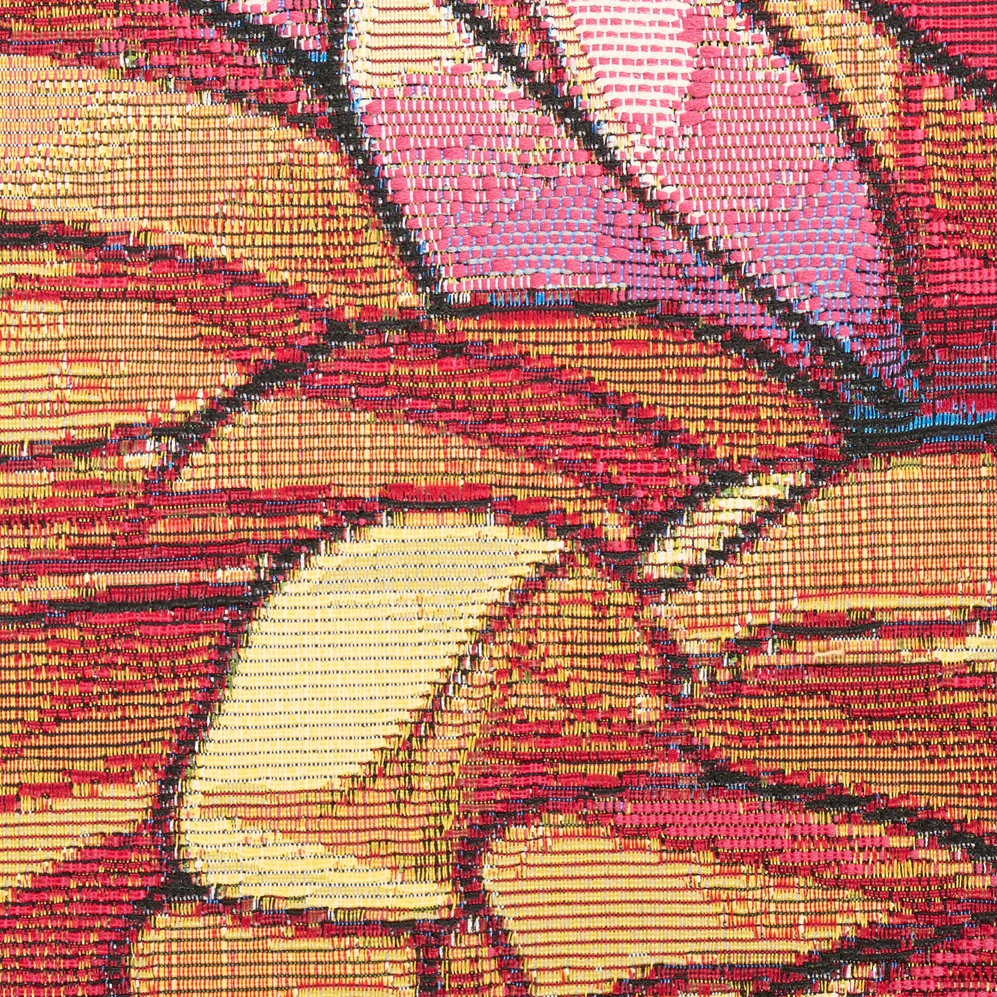 Close-up of a bold, multicolor geometric textile with red, pink, yellow blocks and black outlines.