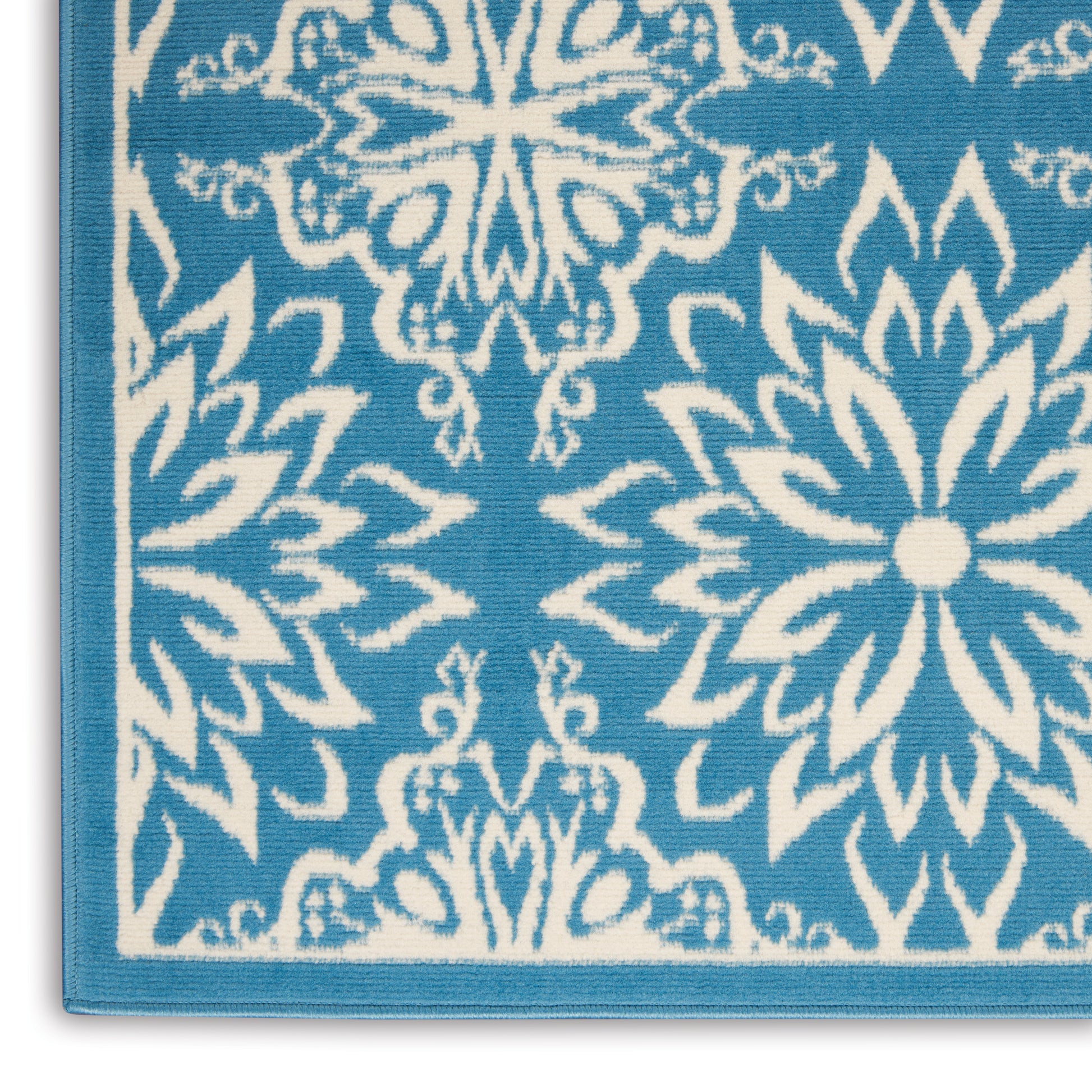 Blue textile with white ornate mandala floral pattern and light blue border.