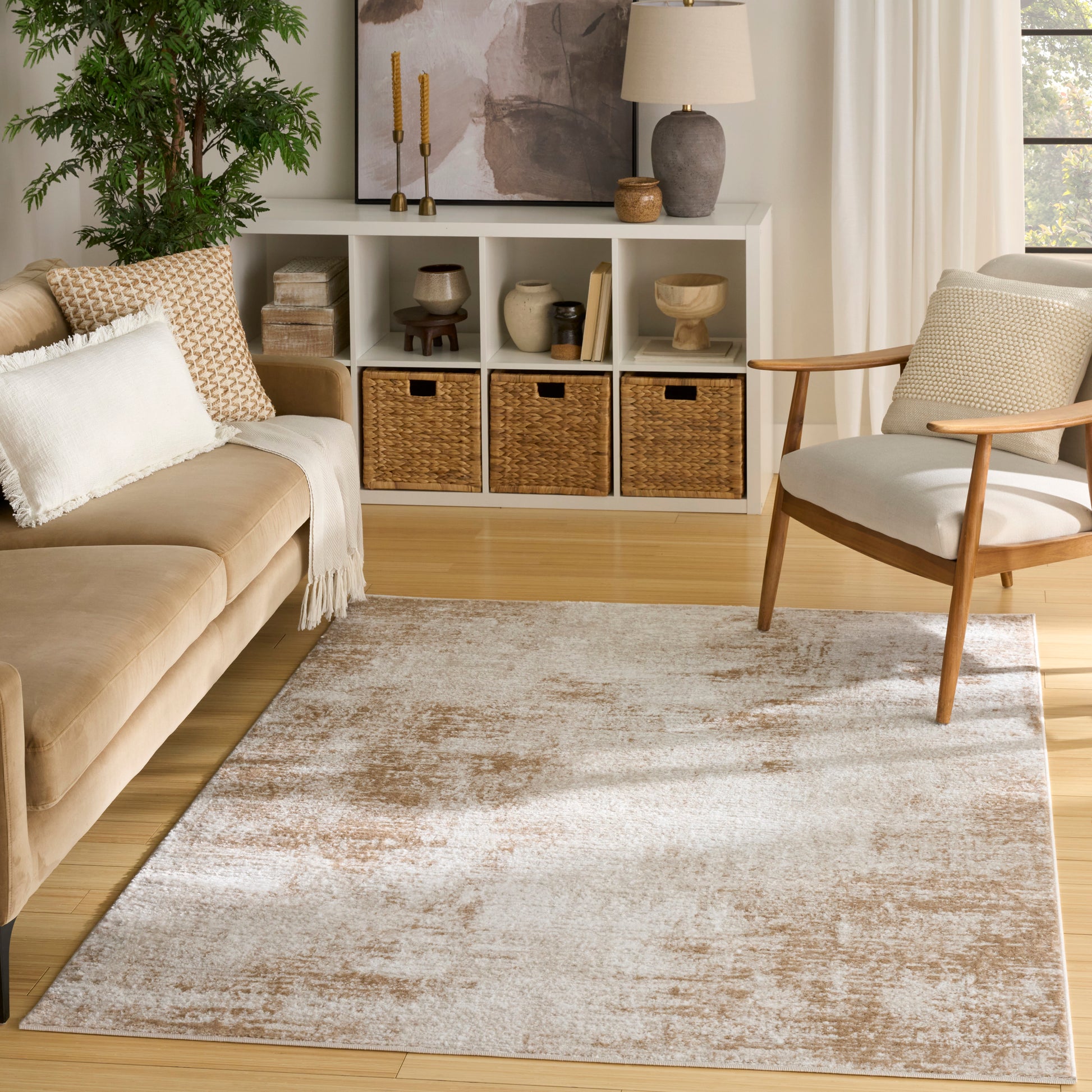 Neutral living room with tan sofa, light wood floors, beige rug, white cubby shelves and wicker baskets; wooden armchair.
