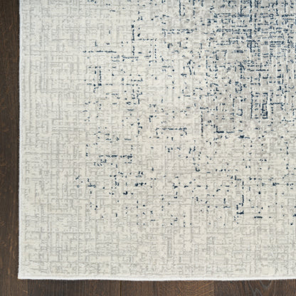 Rectangular cream rug with a subtle blue-gray abstract pattern on dark wood floor.