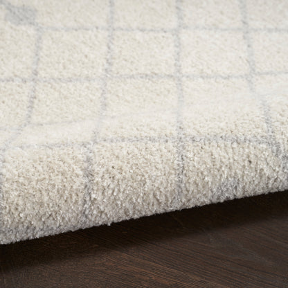 Cream shag rug with pale gray plaid grid, edge folded on dark wood floor.