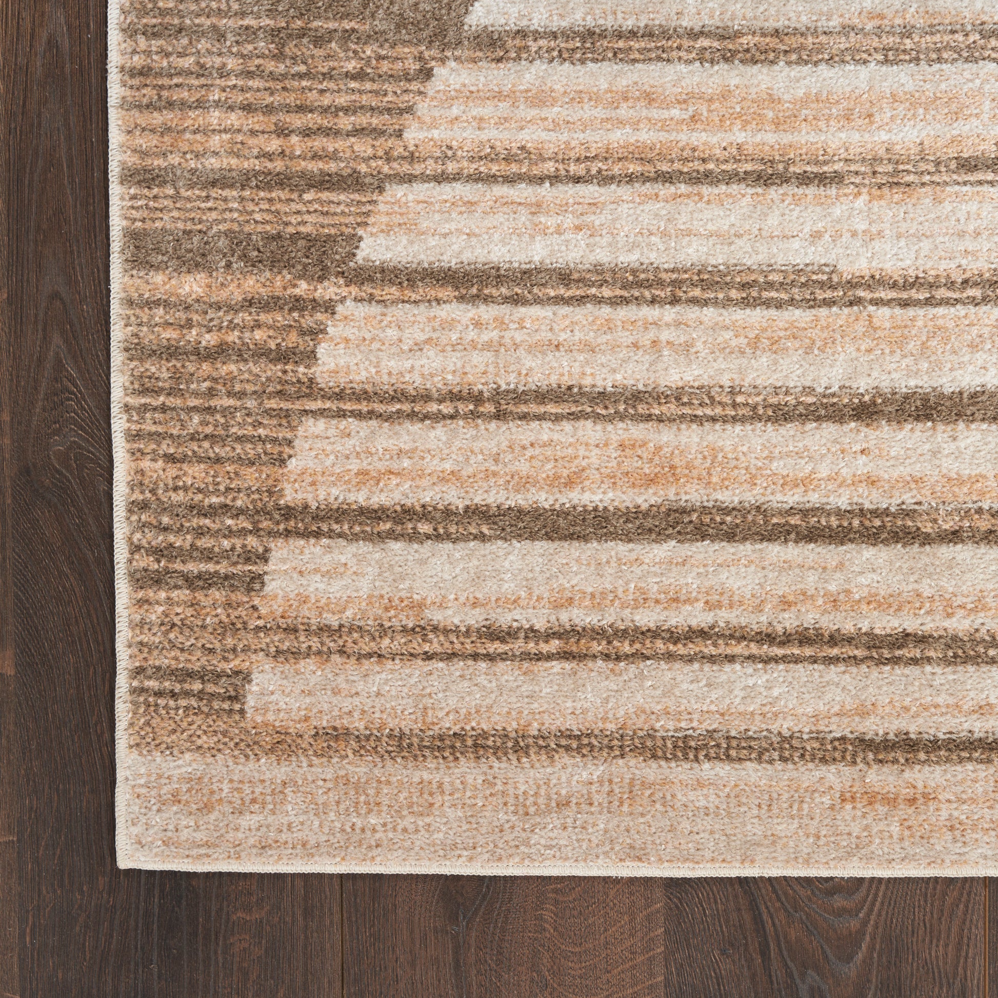 Beige and brown striped rectangular area rug with gradient blocks on dark wood floor, modern geometric style.