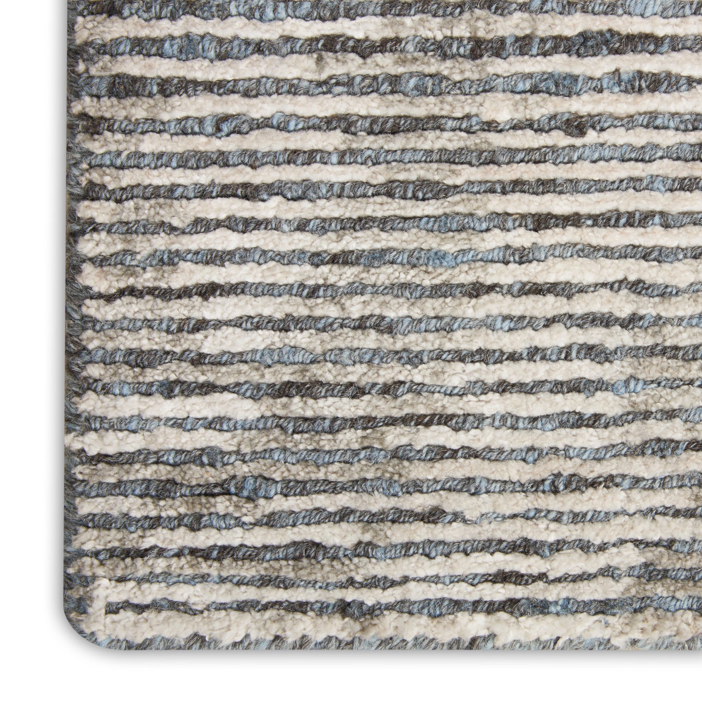 Close-up of a striped textured rug with beige and gray-blue horizontal bands and a rounded corner.