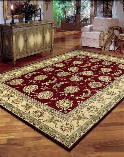 Traditional Persian-style area rug with deep red field and ivory-gold border, ornate floral motif on hardwood living room floor.