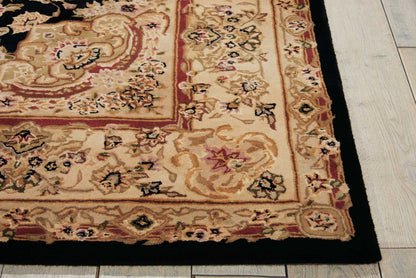 Partial view of an ornate beige Oriental rug with red border, black outer trim, floral motifs, on a wooden floor.