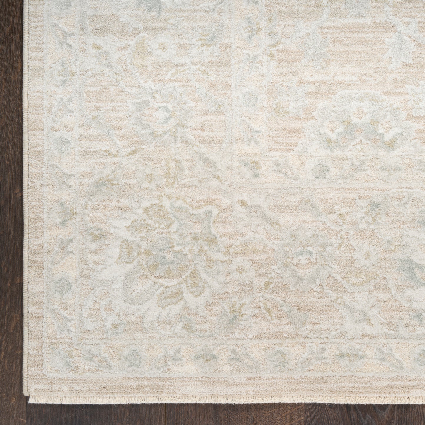 Rectangular cream and pale blue-gray patterned area rug with traditional floral border, flat-weave on dark wood floor.