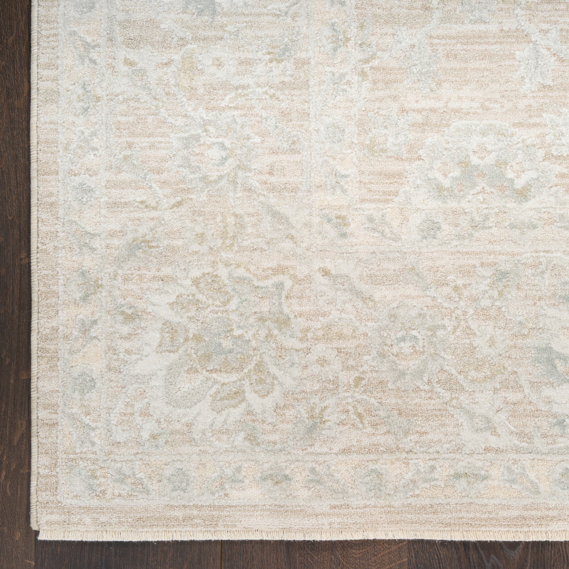 Rectangular cream and pale blue-gray patterned area rug with traditional floral border, flat-weave on dark wood floor.