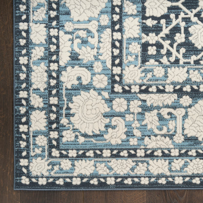 Blue and white oriental rug with floral borders on a dark navy field, laid on a wooden floor.