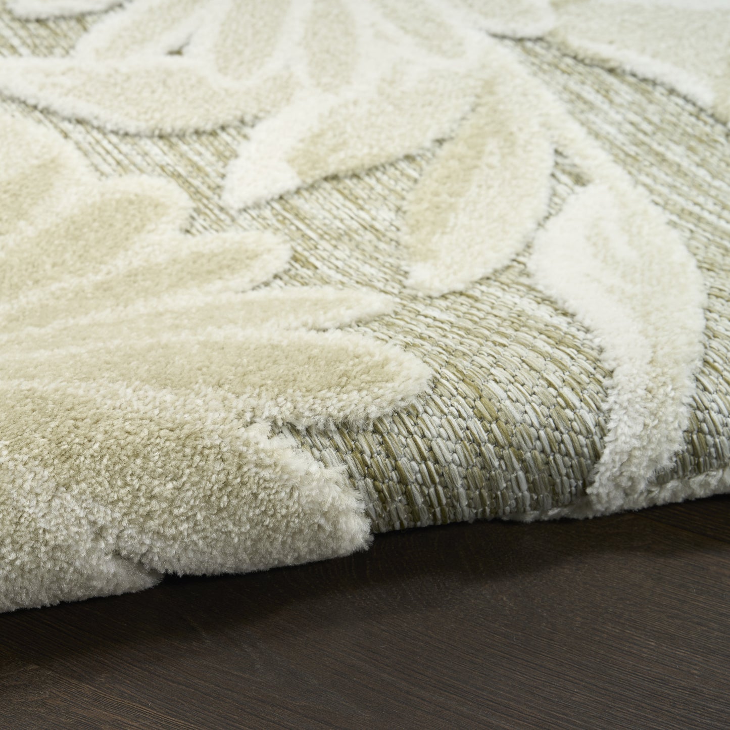 Cream outdoor rug with a raised leaf pattern on a woven beige backing.