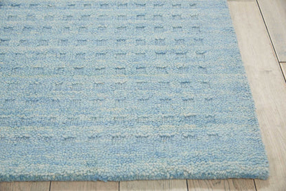 Light blue textured shag rug with pale cream flecks on wooden floor.