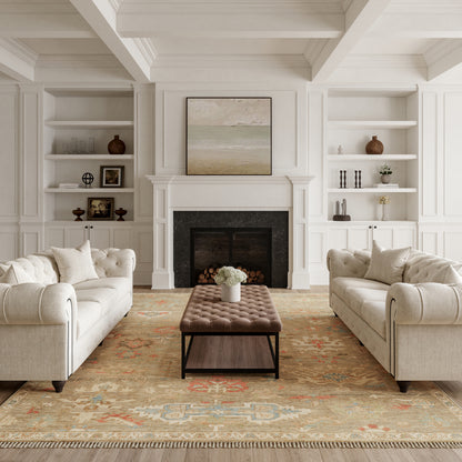 Living room with white-paneled walls and a fireplace, featuring a large vintage rug (9' x 12') on the floor, two beige tufted sofas, a brown tufted ottoman, and built-in shelves.