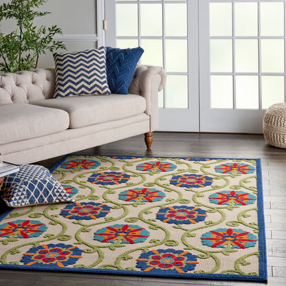 Beige woven rug featuring blue and red floral medallions, green vines and blue border, in living room with cream tufted sofa.
