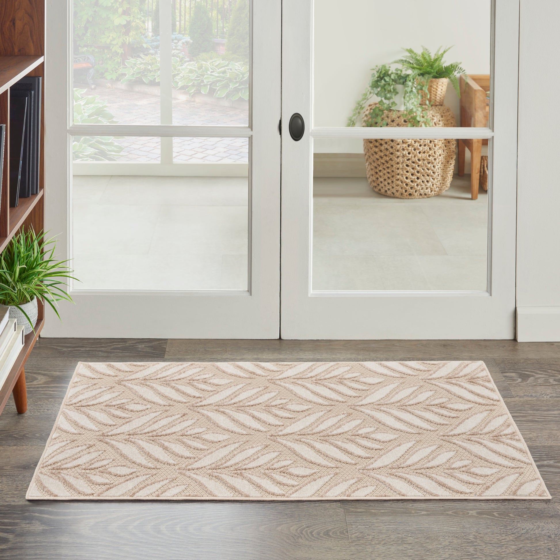 Beige rectangular tropical area rug with embossed leaf pattern for entryway use, placed in front of white glass French doors; 3' x 4'.