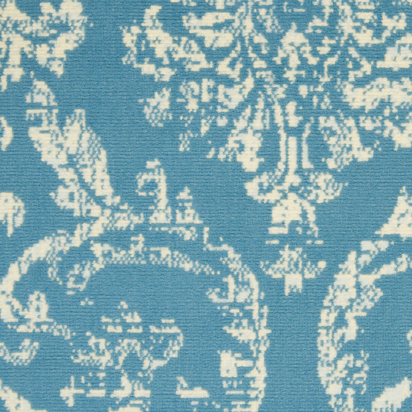 Blue rug with a white damask floral pattern; textured pile, size 6' x 9'.