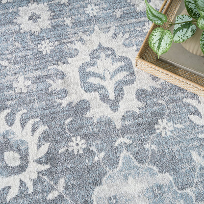 Blue & white damask-patterned rug with a woven basket & leafy plant in the corner.