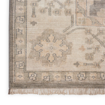 Beige cream oriental rug with pale blue-gray floral medallion, geometric border, and fringe.