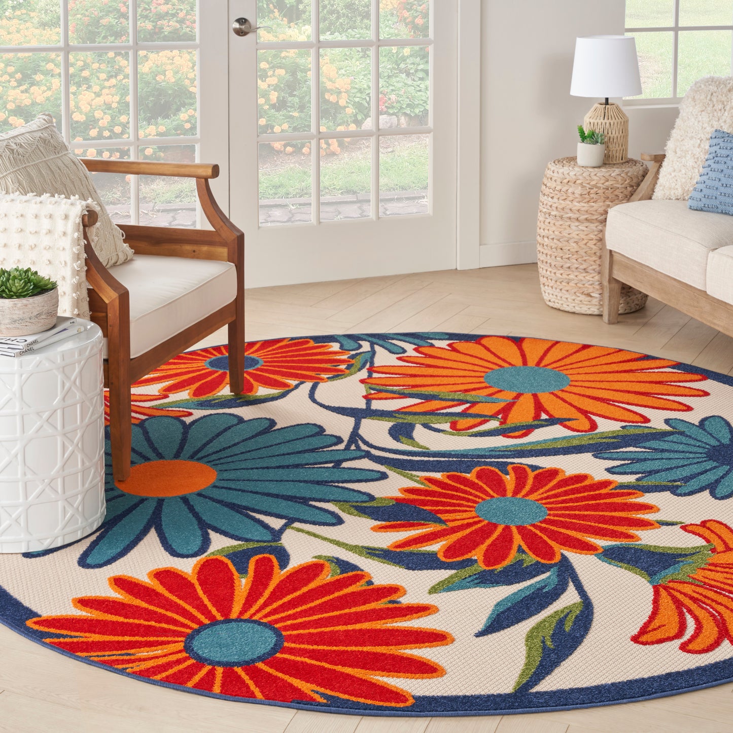 Round floral area rug with bright orange and blue flowers on a beige background with a navy border in a cozy living room.