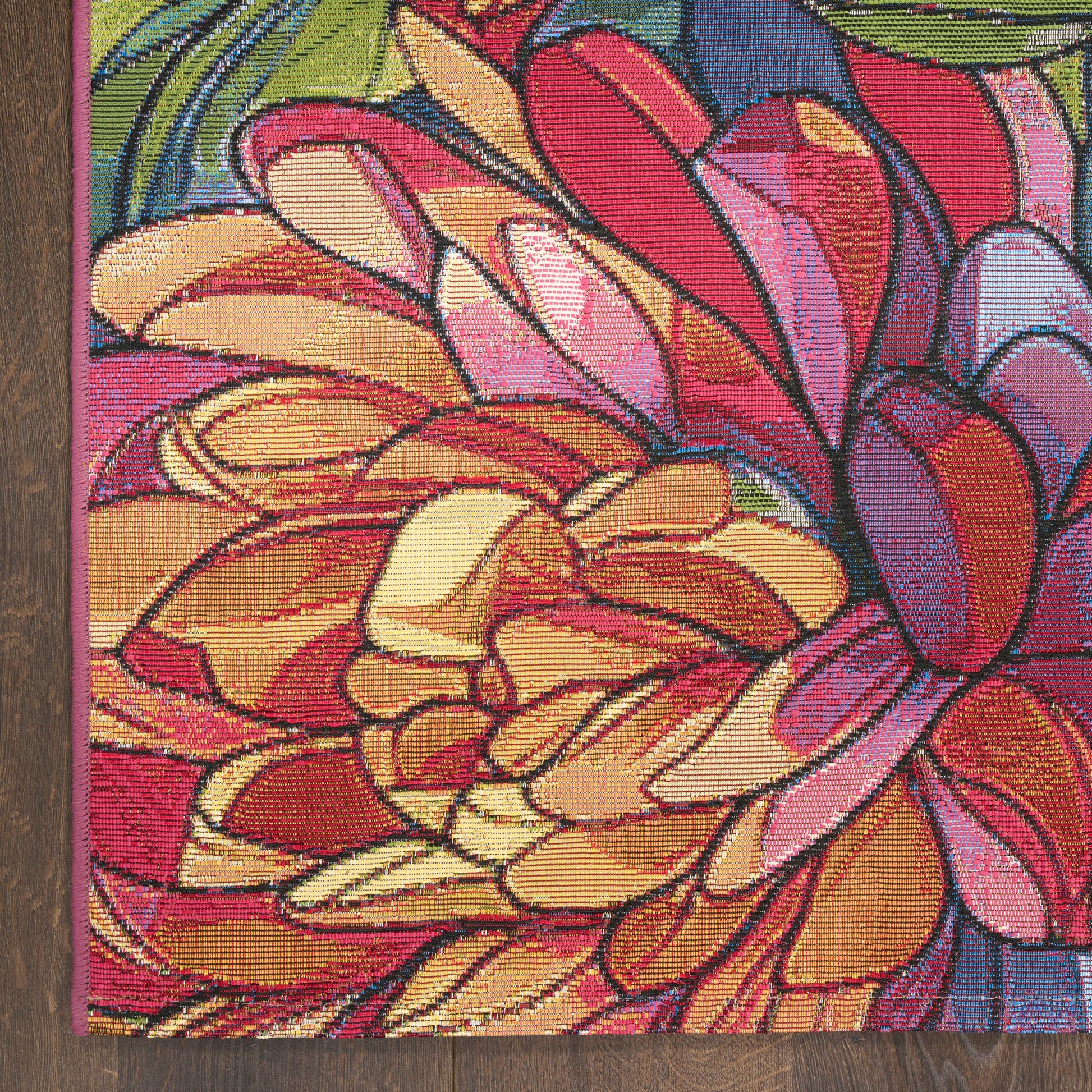 Outdoor rug with a vibrant floral pattern of overlapping multicolor petals in yellow, orange, pink, red and purple; woven texture, purple edge; 4' x 6'.
