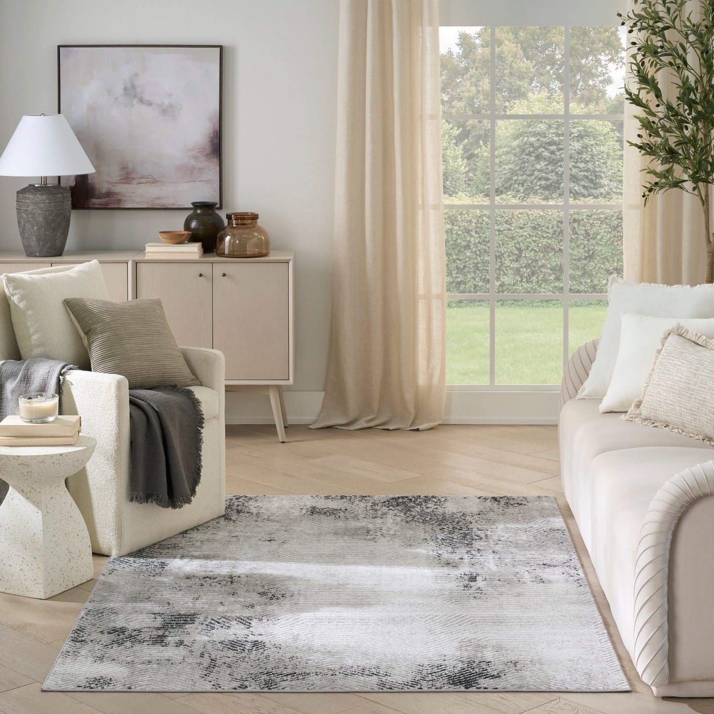 Neutral abstract area rug in gray, white, and black tones, modern living room with light wood floor.