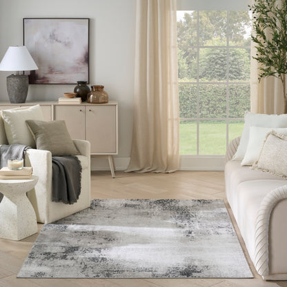 Neutral abstract area rug in gray, white, and black tones, modern living room with light wood floor.