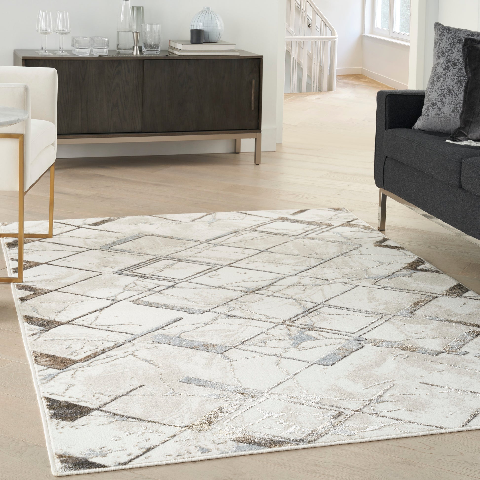 Rectangular neutral area rug with abstract geometric pattern in beige, gray and taupe.