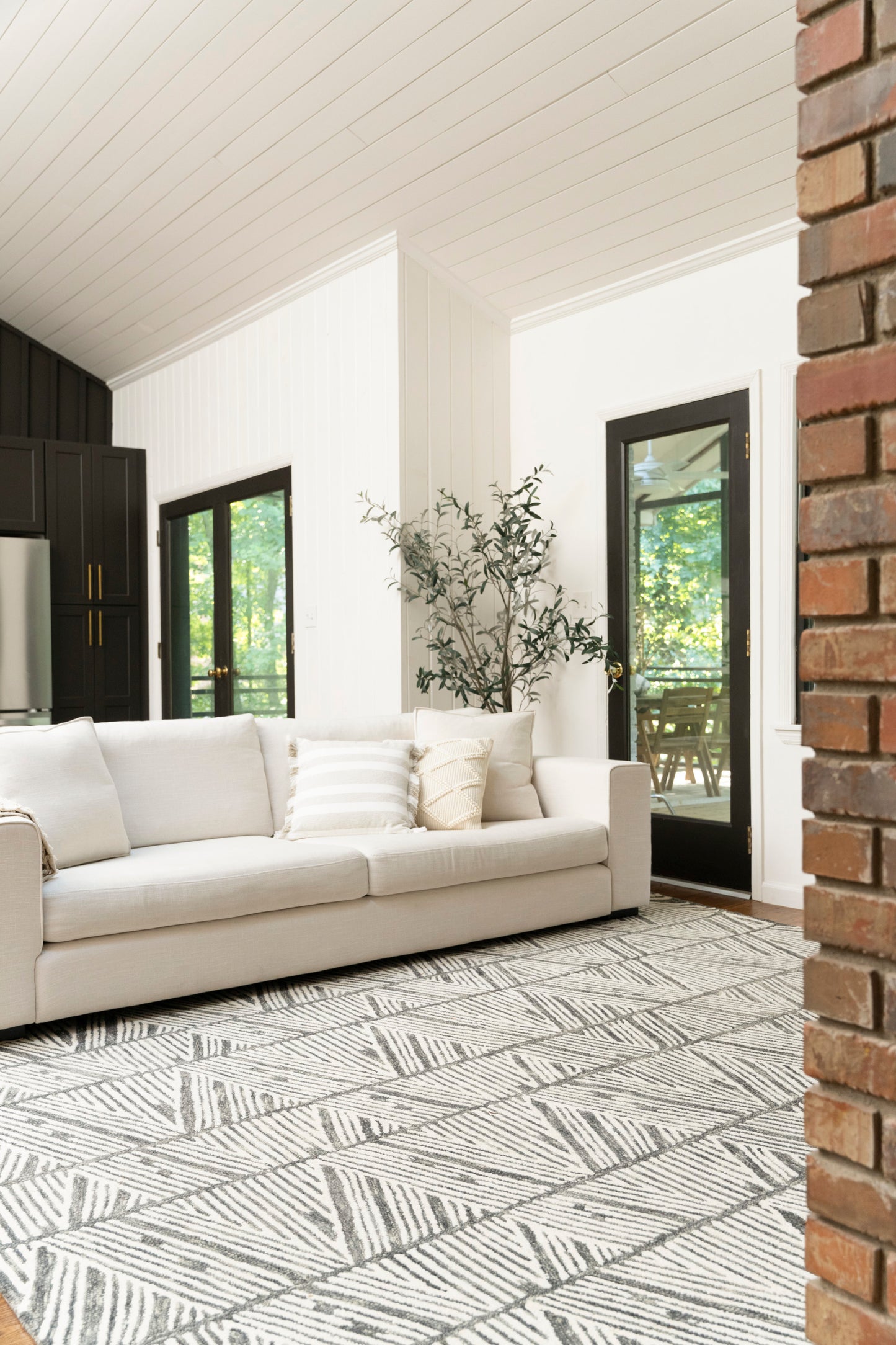 Light beige geometric leaf rug in a white-paneled living room with black-framed doors.