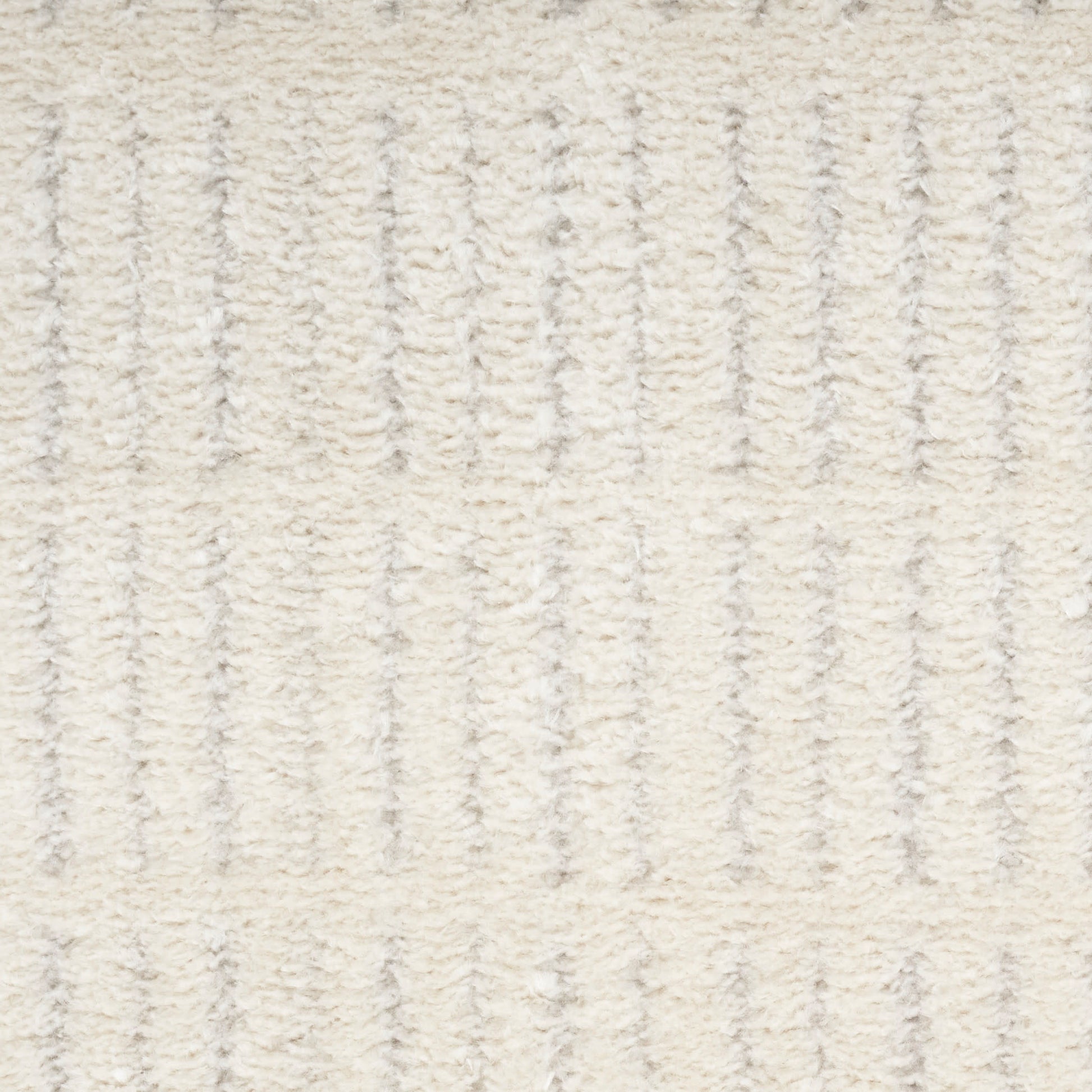 Cream textured rug with vertical ribbed pattern in ivory and beige; soft plush surface for living room decor.
