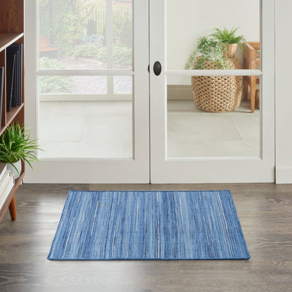 Blue striped rectangular entry rug on wood floor in front of glass French doors, with potted plants nearby.