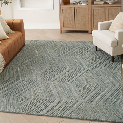 Blue-gray geometric area rug with chevron zigzag pattern in living room, paired with a tan leather sofa and white armchair.