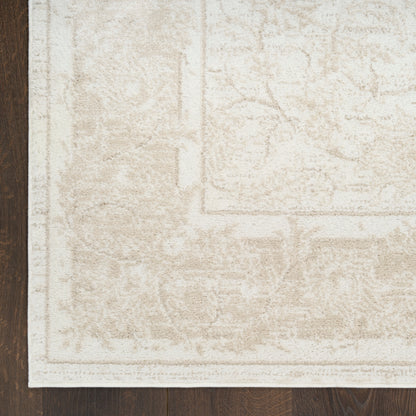 Cream-colored area rug with a subtle distressed pattern & light border on dark wood floor.