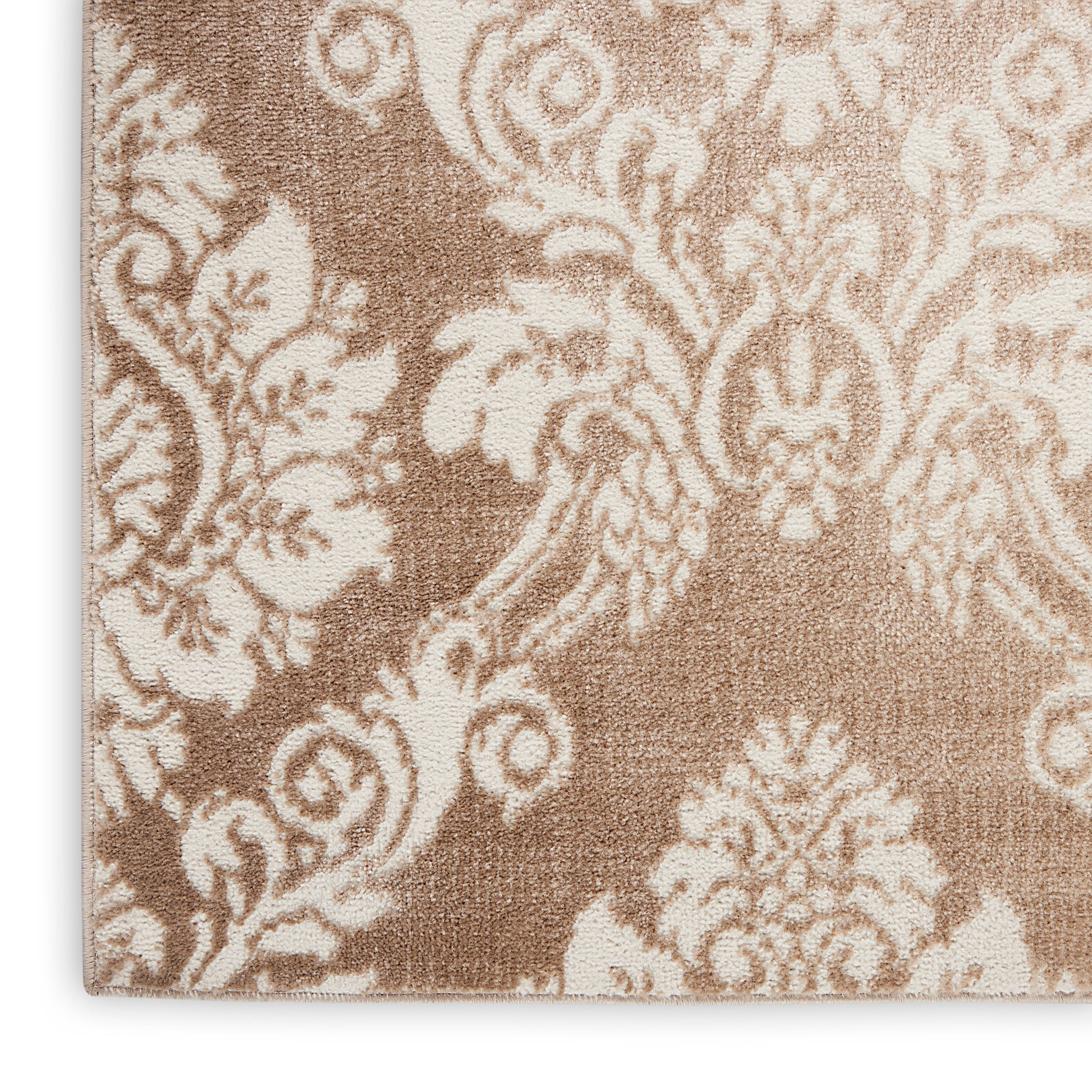 Beige damask patterned rug close-up, ornate floral motif on a soft brown background.