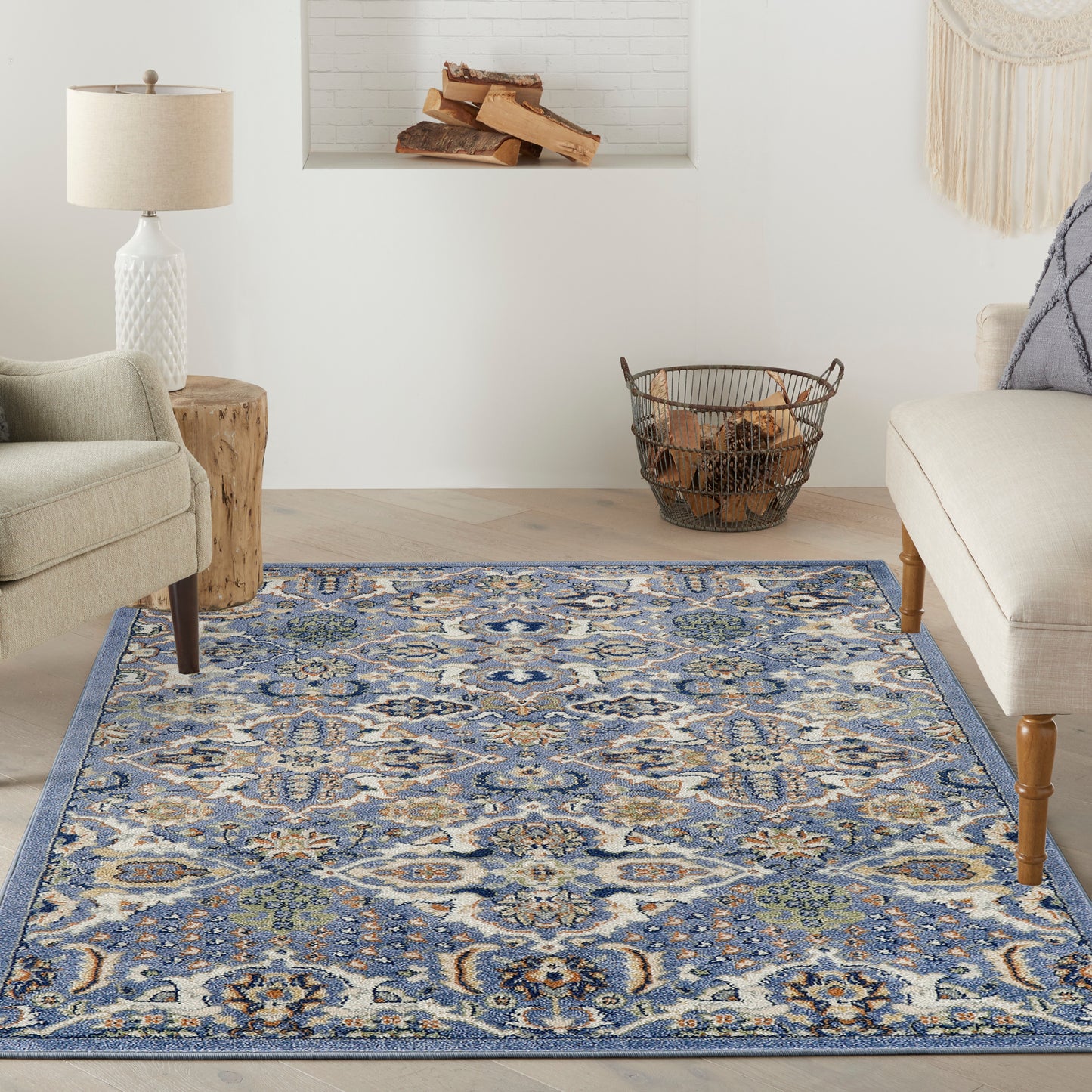 Blue patterned area rug in a living room with beige chairs, a wood stump side table, and a log basket.