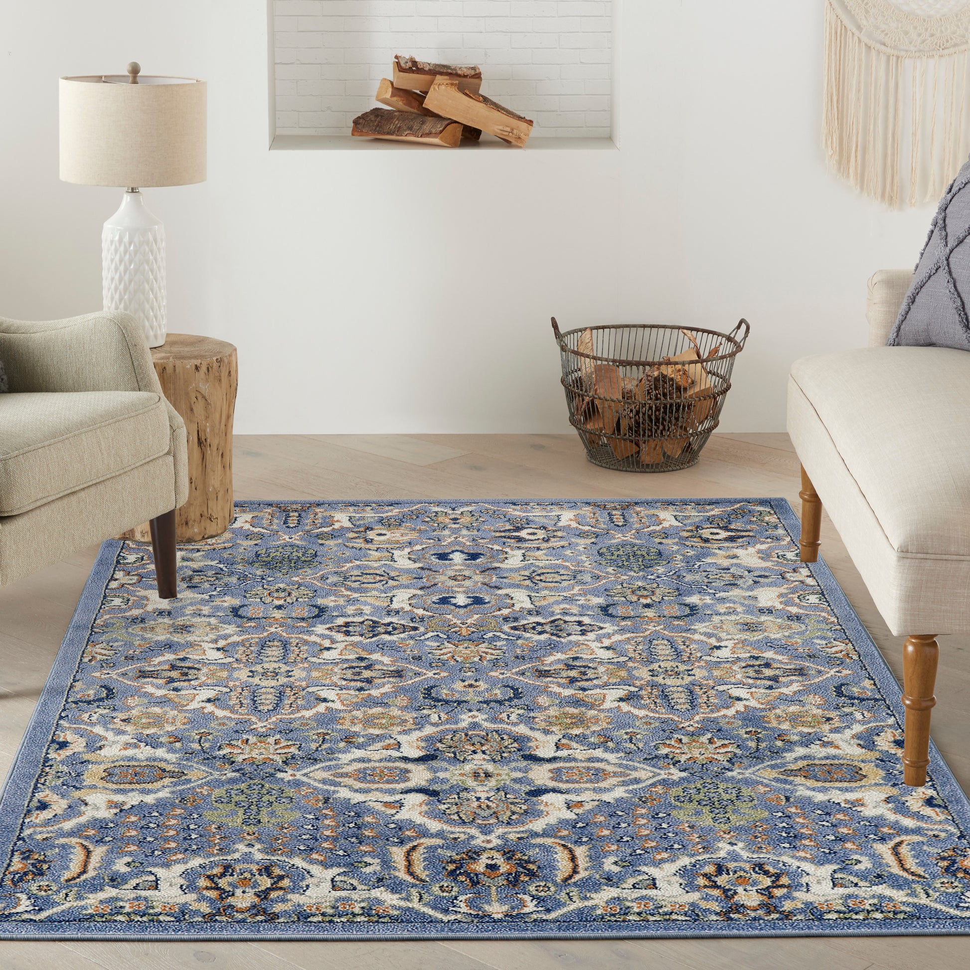 Blue patterned area rug in a living room with beige chairs, a wood stump side table, and a log basket.