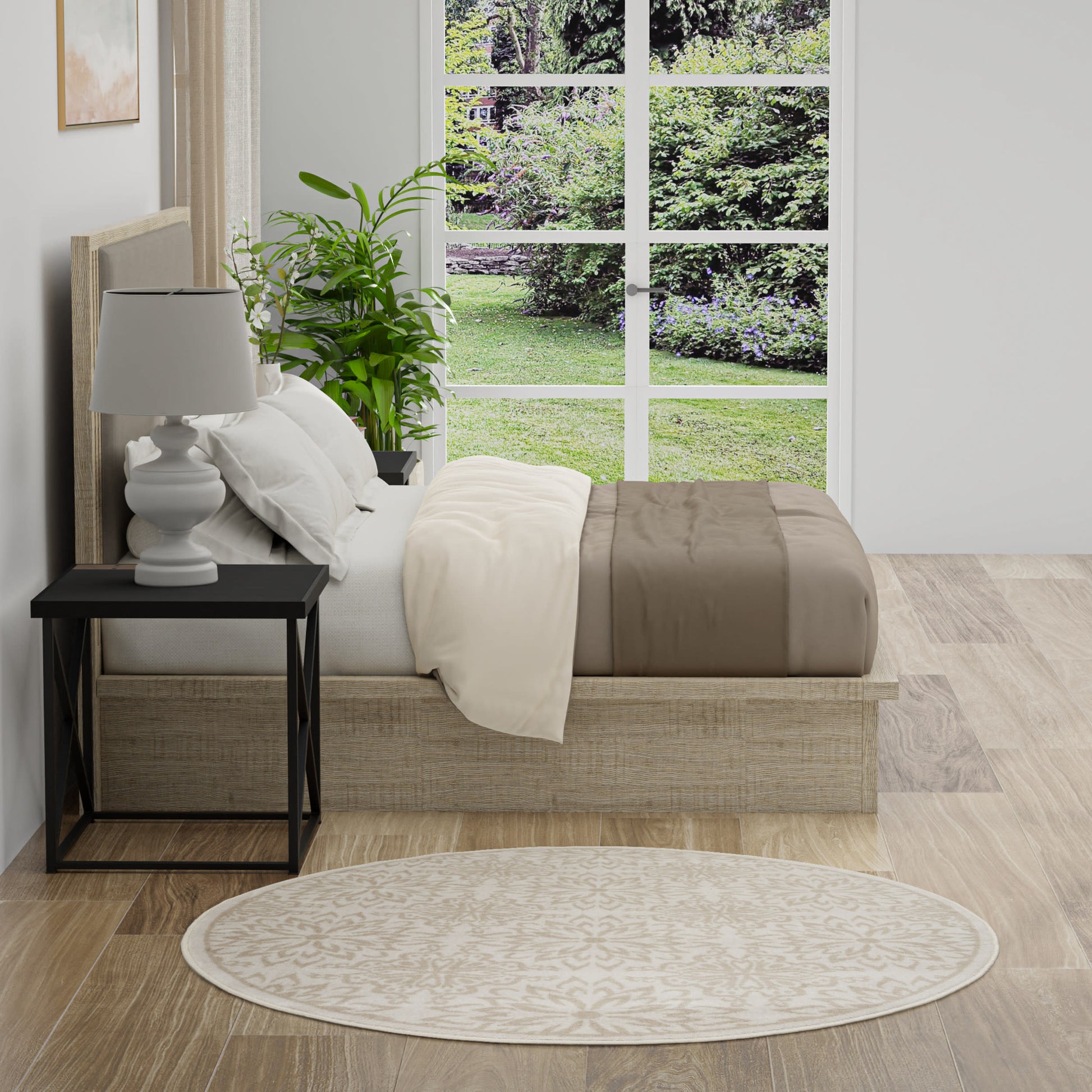 Neutral bedroom with a low platform bed, white and beige bedding, black nightstand, white lamp, plant, round beige rug.