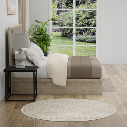 Neutral bedroom with a low platform bed, white and beige bedding, black nightstand, white lamp, plant, round beige rug.