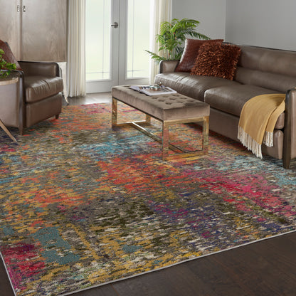 Living room with a vibrant multicolor abstract rug, taupe tufted ottoman on gold legs, and brown leather sofa.