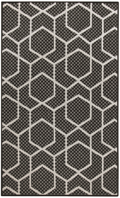 Black and white geometric rug with interconnected hexagons and dotted interiors; modern flat-weave style.