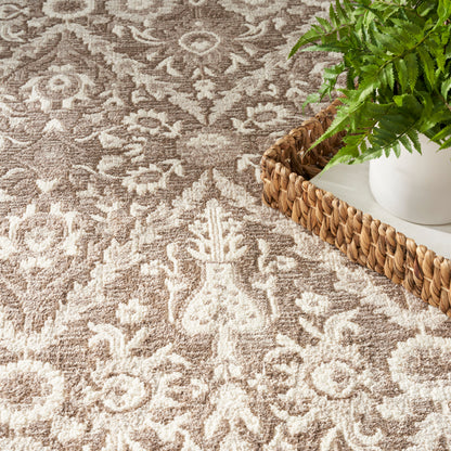 Beige and tan ornate patterned rug with a woven rattan tray holding a white planter and green fern.