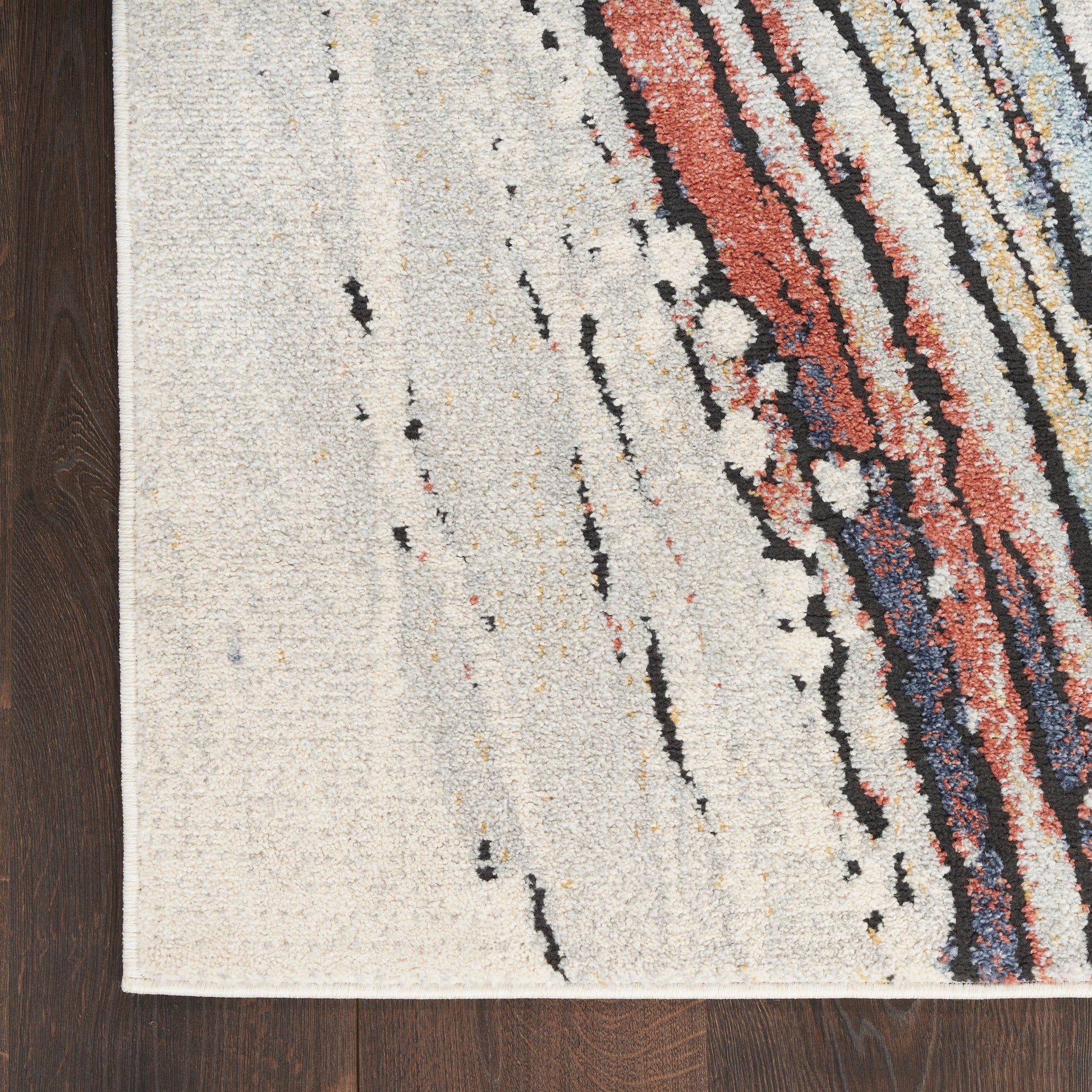 Rectangular modern area rug with cream base and multicolor diagonal stripe pattern in red, orange, blue and black.