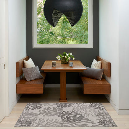 Wooden corner booth with square pedestal table, gray wall, white flowers, botanical rug, and black circular pendant light.