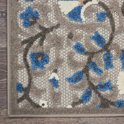Beige and brown floral area rug with blue accent flowers, low-pile textile, rectangular, on wood floor.