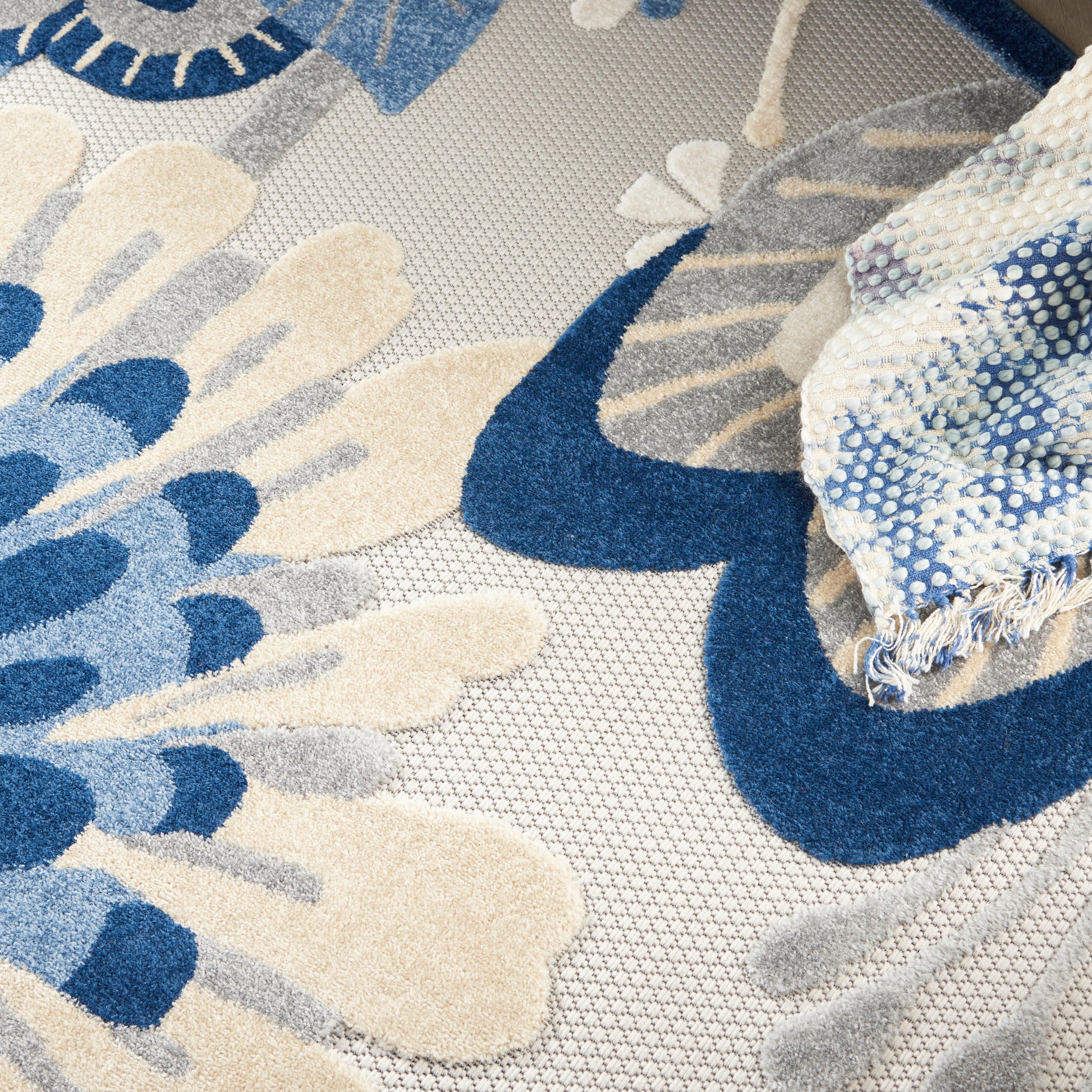 Blue and ivory floral woven rug with beige accents, textured jacquard pattern and fringed edge