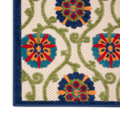 Corner of a colorful floral rug with blue border, cream background, green vines & red, orange, blue flowers.