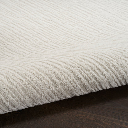 Cream textured rug with ribbed plush pile on dark wood floor; cozy, modern living room accent.