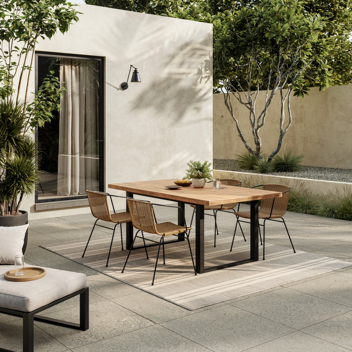 Outdoor dining set: rectangular wooden table with black metal legs and six woven rattan chairs in a modern courtyard.
