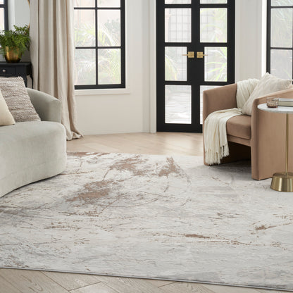 Neutral living room with beige fabric sofas, cream throw, gold side table, abstract gray rug, black framed doors and big windows.