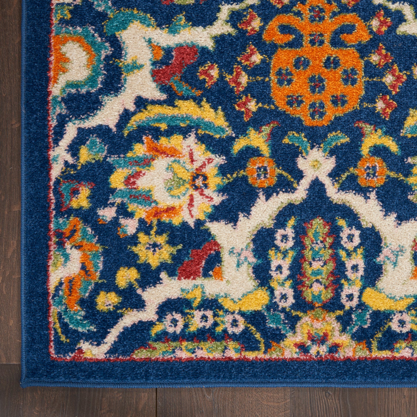 Colorful oriental rug corner with deep blue background, vibrant floral motifs and orange medallion, multicolor border.