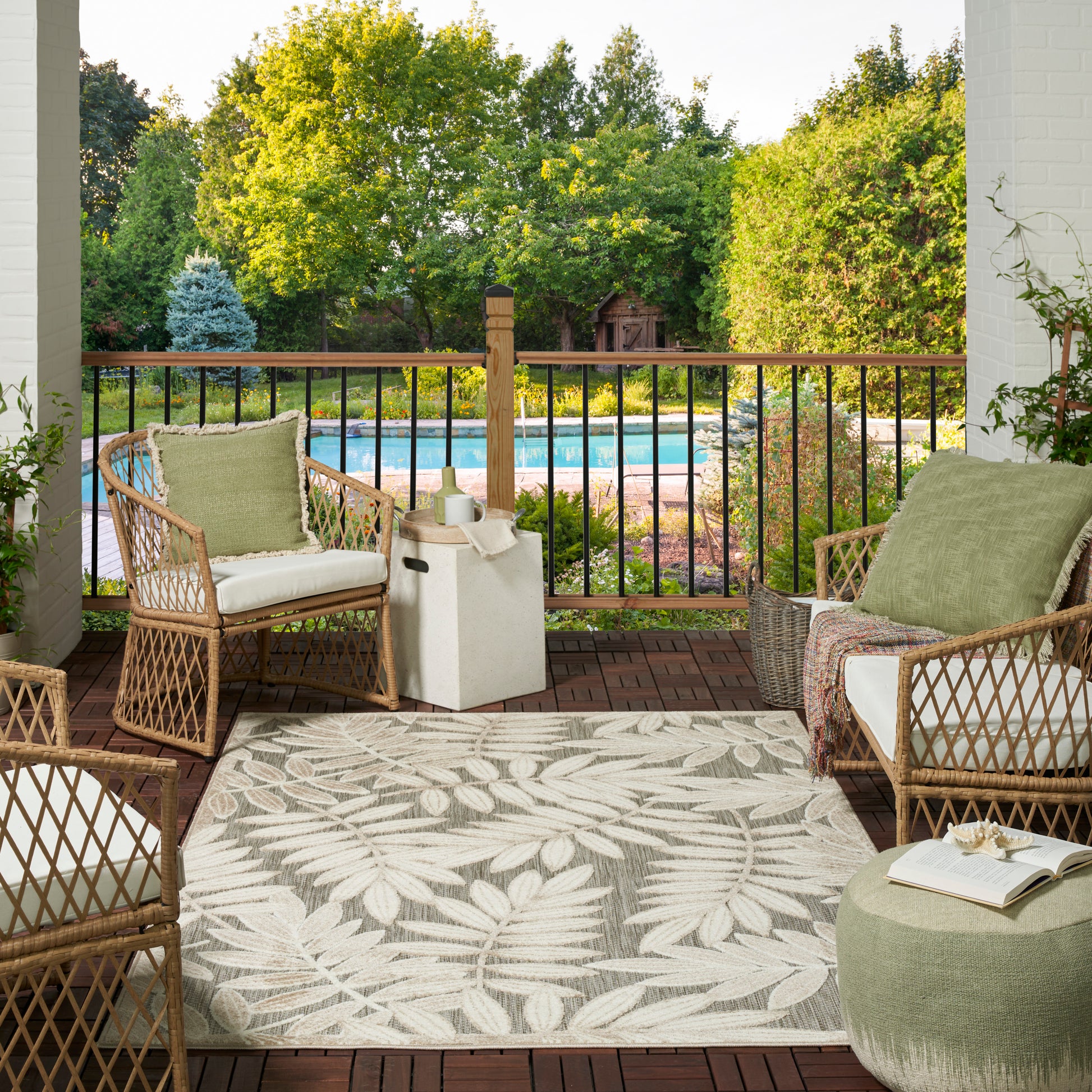 Tropical leaf-pattern outdoor rug on a wooden deck near a pool, 6' x 9'.