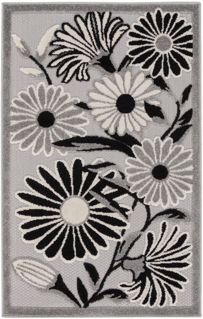 Rectangular grey area rug with bold black-and-white daisy flowers and a subtle border.