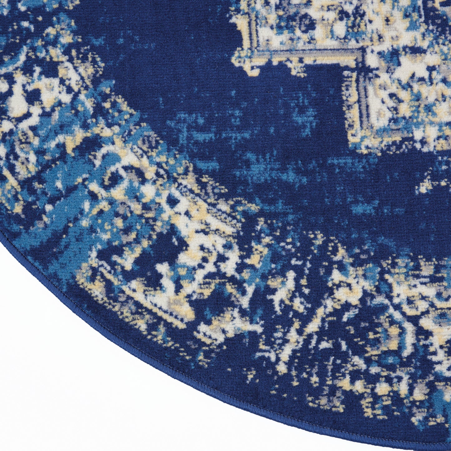 Round navy blue rug with distressed abstract pattern in light blue and beige; soft textured pile with dark blue binding.